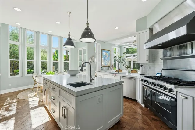 a kitchen with stainless steel appliances granite countertop a sink a stove and a wooden floors