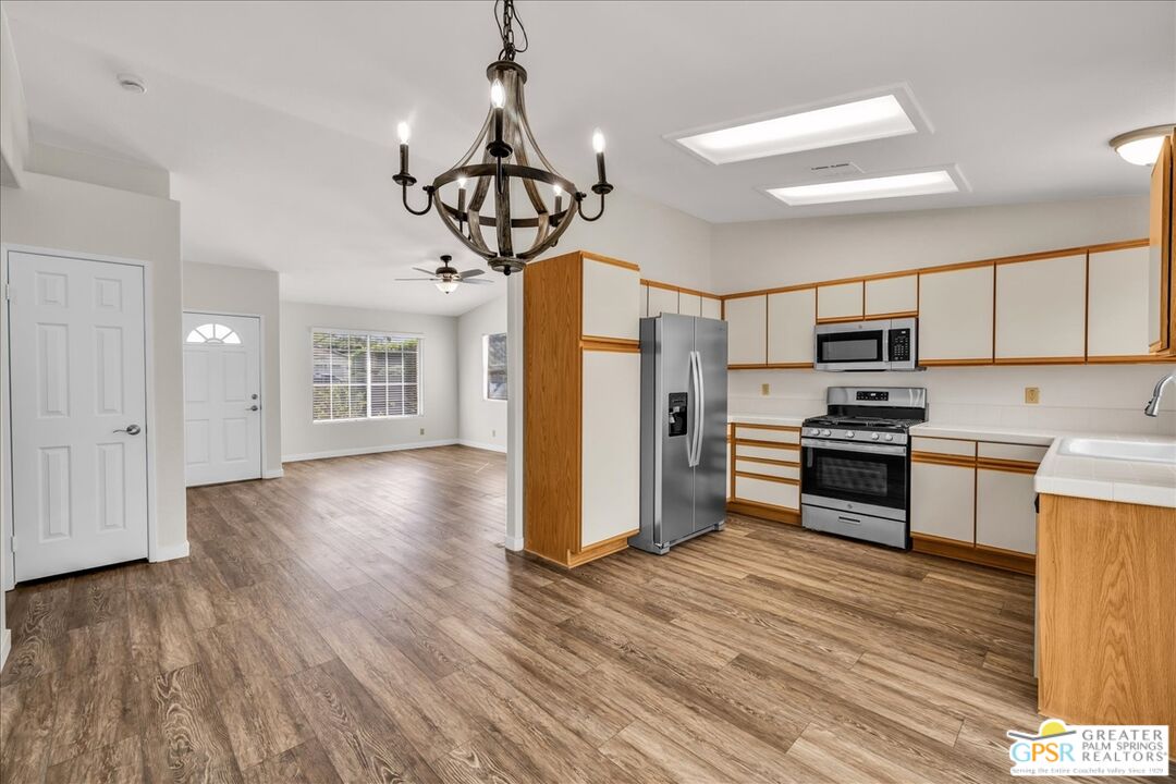 68130 Hermosillo Road Cathedral City, CA 92234 - Photo 15 of 49 a kitchen with stainless steel appliances granite countertop a refrigerator a stove top oven a sink dishwasher and white cabinets with wooden floor