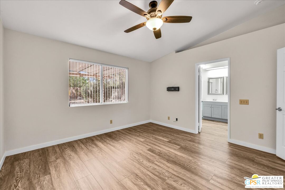 68130 Hermosillo Road Cathedral City, CA 92234 - Photo 25 of 49 an empty room with wooden floor chandelier fan and windows