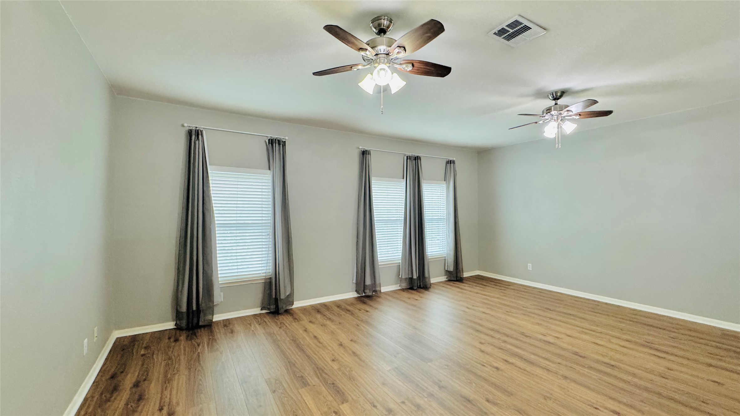 401 Witte Road Kyle, TX 78640 - Photo 13 of 24 Upper level-Well-lit living area featuring multiple windows with blinds and rich hardwood flooring throughout.