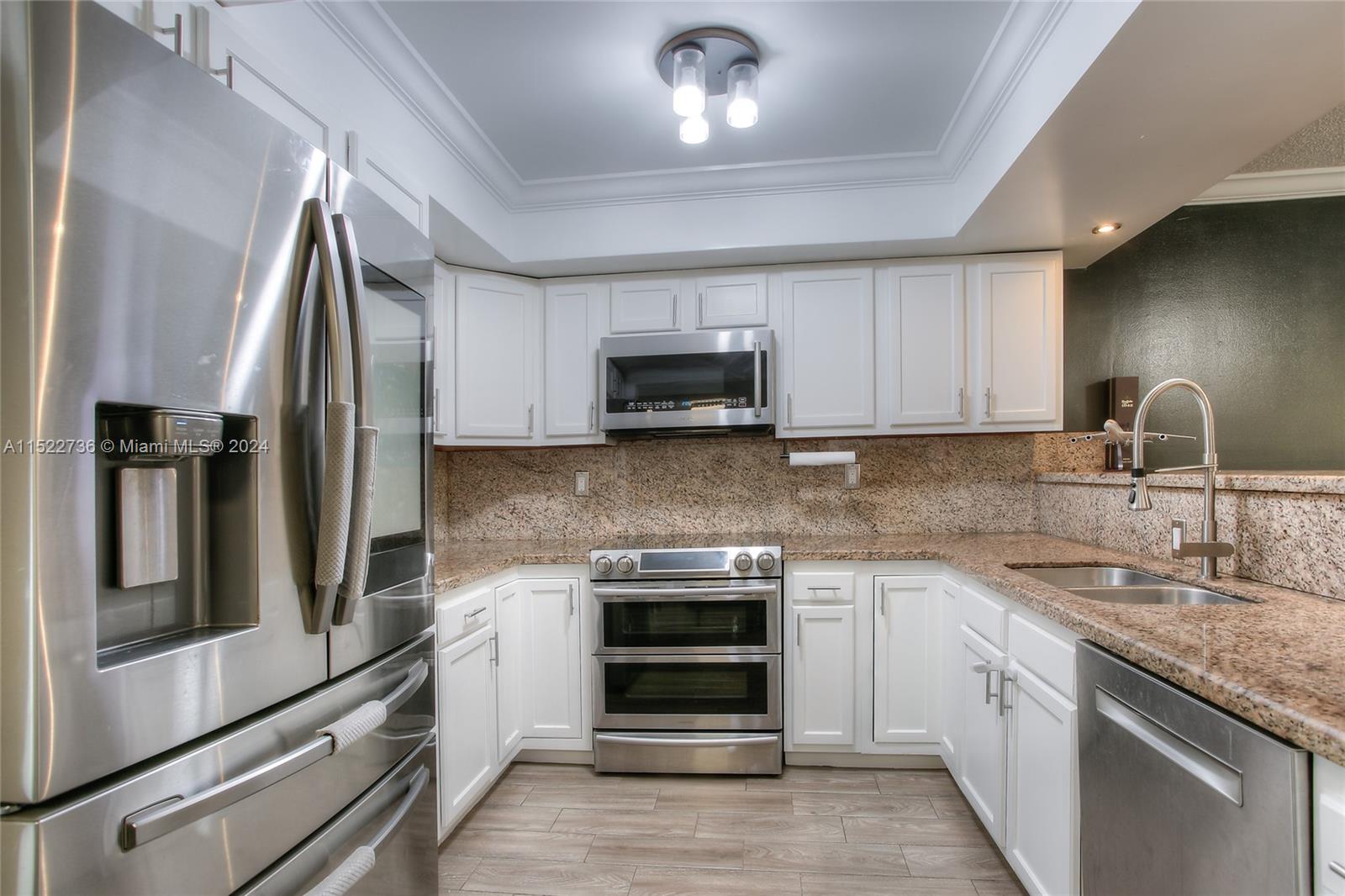 a kitchen with granite countertop a sink and stainless steel appliances
