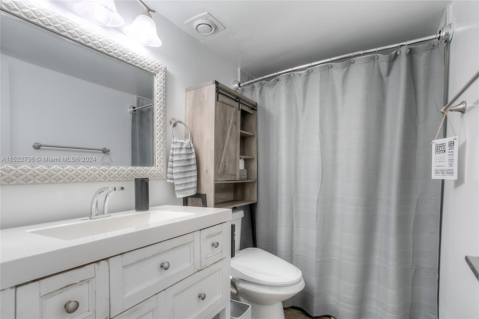 8401 West Sample Road, Unit 35 Coral Springs, FL 33065 - Photo 9 of 13 a bathroom with a sink a toilet a mirror and shower curtain
