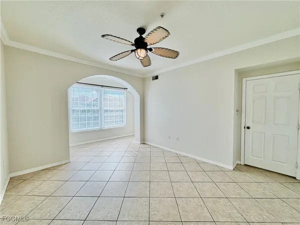 a view of an empty room and chandelier fan