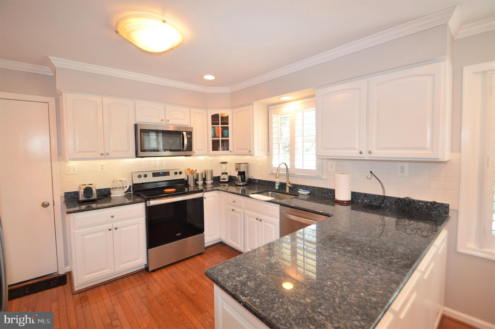 12614 Oxon Road Herndon, VA 20171 - Photo 30 of 71 a white kitchen with granite countertop a stove top oven a sink a counter space and cabinets