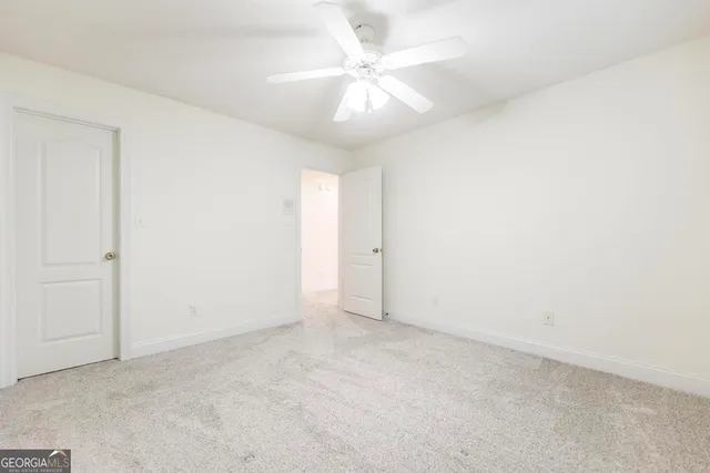 an empty room with a chandelier fan and windows