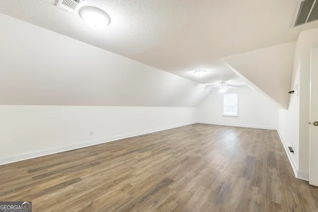 a view of an empty room with wooden floor and stairs