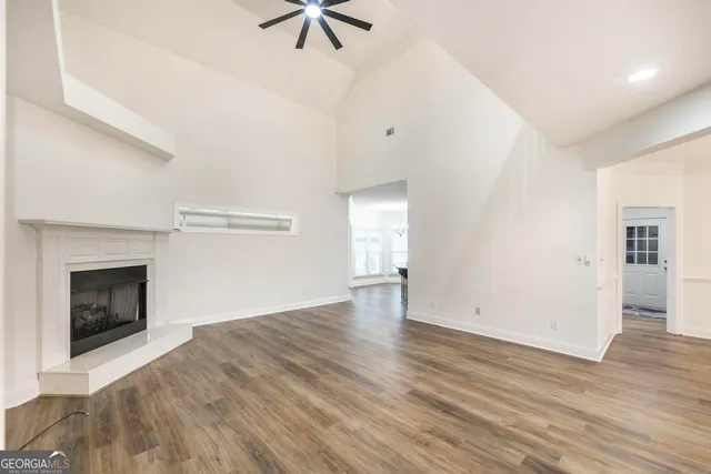an empty room with wooden floor fireplace and windows