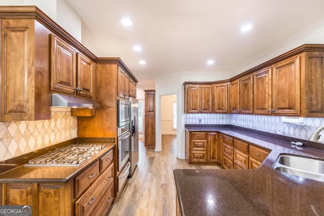 a kitchen with stainless steel appliances granite countertop a stove a sink and a refrigerator