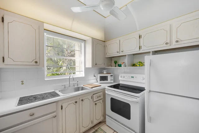 a kitchen with granite countertop white cabinets and white appliances