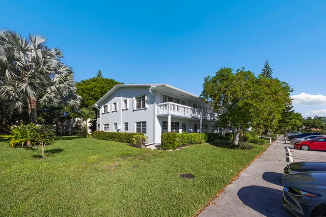 a view of a house with a big yard plants and large trees