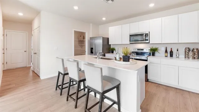 a kitchen with stainless steel appliances a dining table chairs refrigerator and sink
