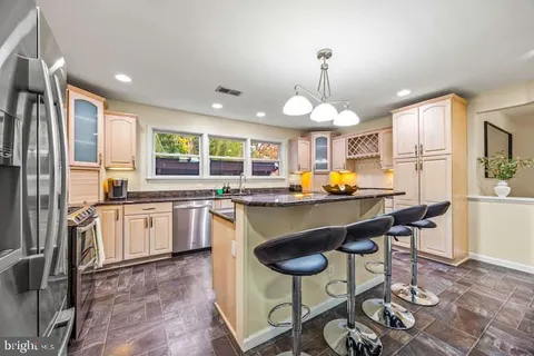 a kitchen with a sink refrigerator and chairs
