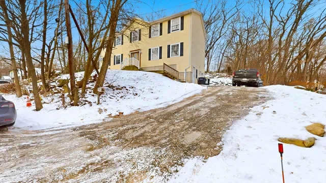 a view of a white house next to a road with a covered with snow