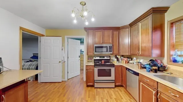 a kitchen with stainless steel appliances a stove a sink a refrigerator cabinets and wooden floor