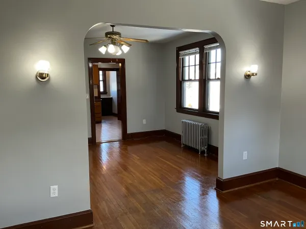 a view of an empty room with wooden floor and a window
