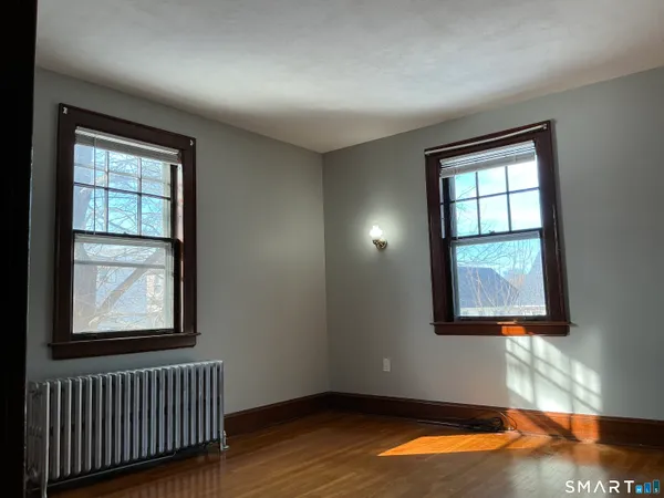 a view of empty room with wooden floor and fan