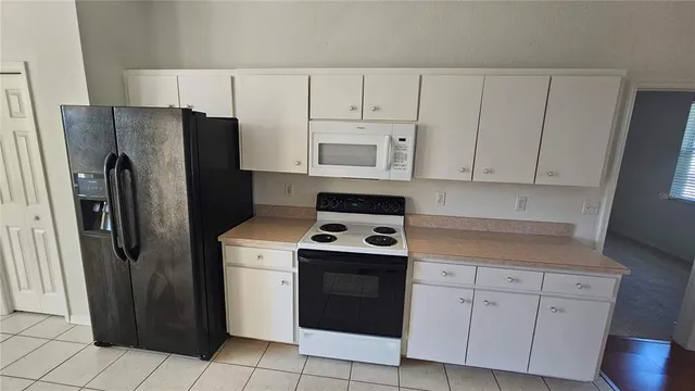 a kitchen with white cabinets and refrigerator