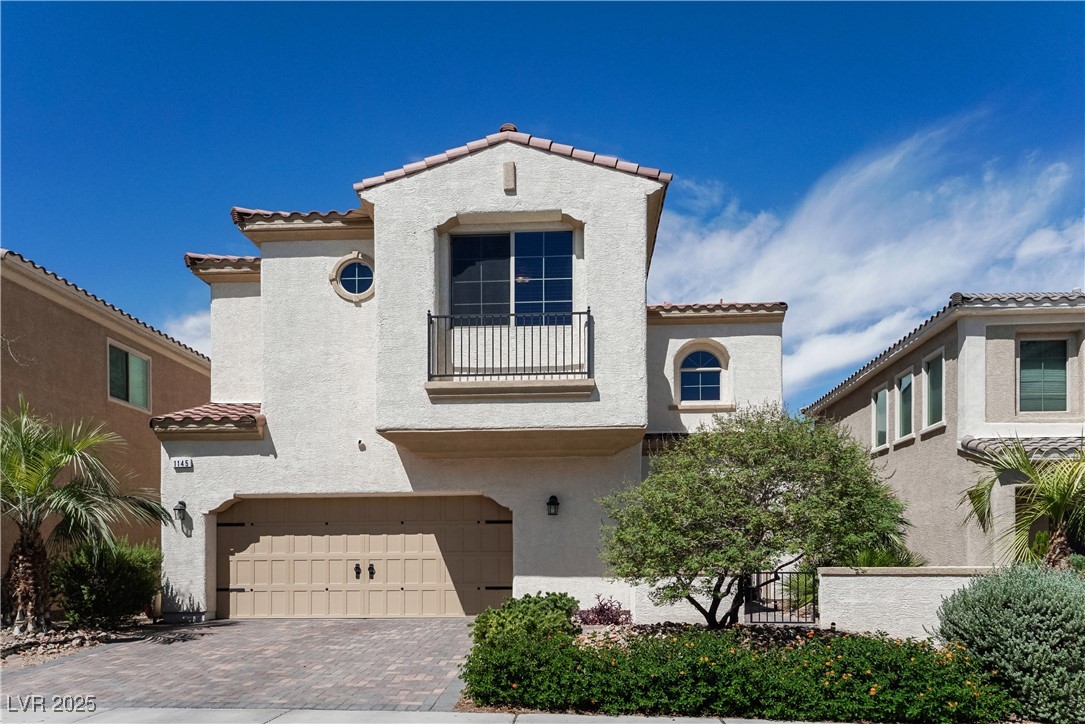 Mediterranean / spanish home with a tiled roof, an attached garage, stucco siding, and decorative driveway
