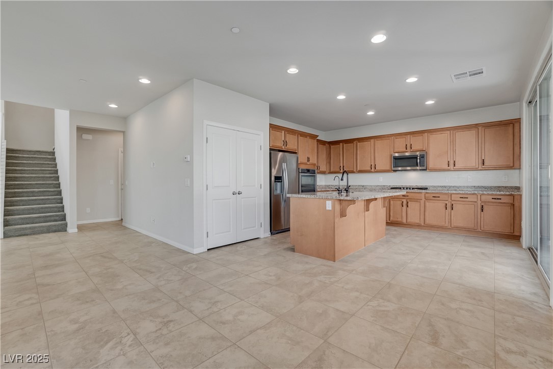 1145 Strada Pecei Henderson, NV 89011 - Photo 12 of 61 Kitchen with recessed lighting, a kitchen breakfast bar, appliances with stainless steel finishes, a kitchen island with sink, and light stone countertops
