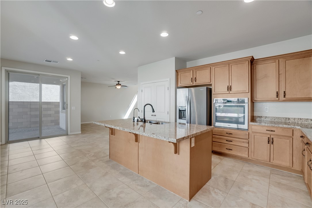 1145 Strada Pecei Henderson, NV 89011 - Photo 13 of 61 Kitchen featuring stainless steel appliances, light stone counters, recessed lighting, a kitchen breakfast bar, and a kitchen island with sink