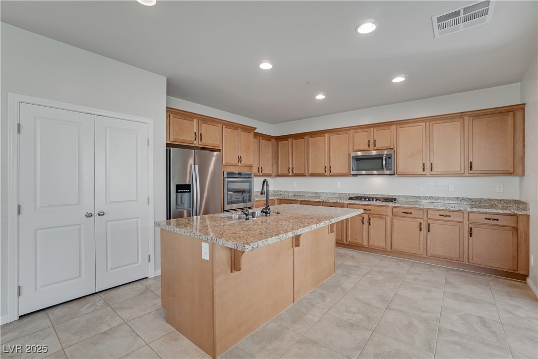 1145 Strada Pecei Henderson, NV 89011 - Photo 16 of 61 Kitchen featuring recessed lighting, appliances with stainless steel finishes, a kitchen island with sink, light stone countertops, and a breakfast bar area