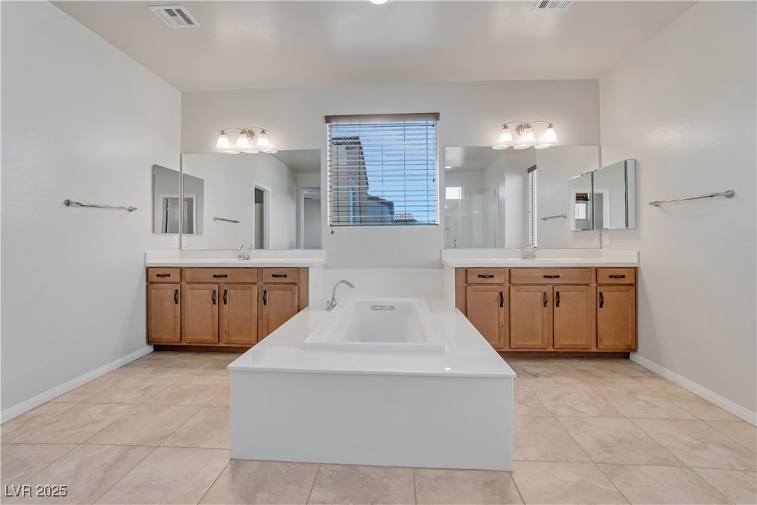 1145 Strada Pecei Henderson, NV 89011 - Photo 26 of 61 Full bathroom with a garden tub, two vanities, and tile patterned flooring