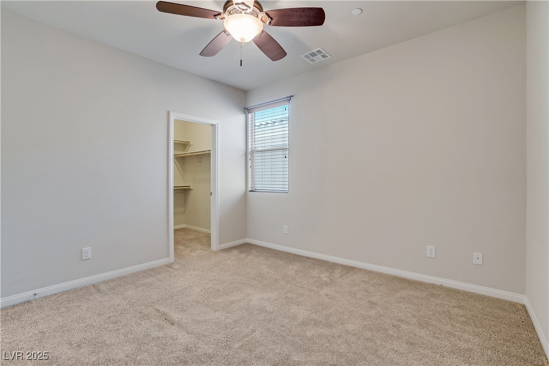1145 Strada Pecei Henderson, NV 89011 - Photo 29 of 61 Unfurnished bedroom with light carpet, a walk in closet, and a ceiling fan