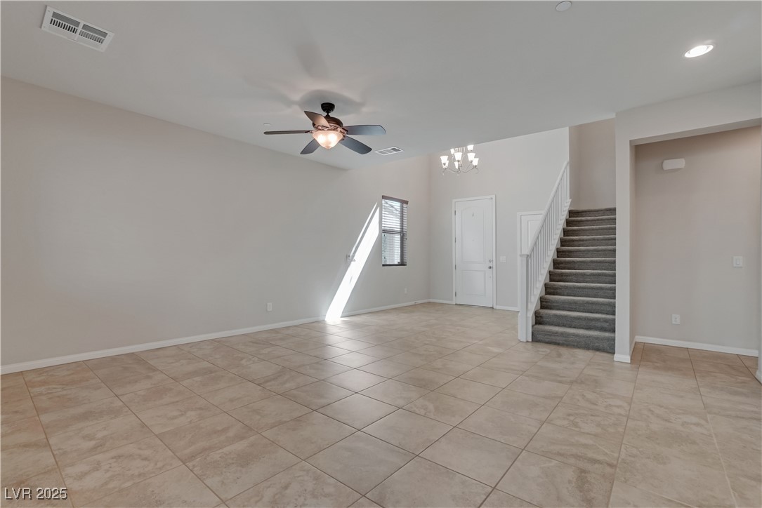 1145 Strada Pecei Henderson, NV 89011 - Photo 7 of 61 Empty room with stairs, ceiling fan, a chandelier, and light tile patterned flooring