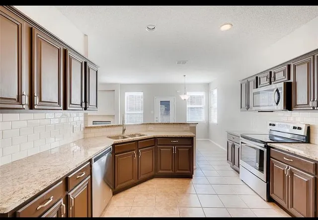 a large kitchen with stainless steel appliances granite countertop a sink and cabinets
