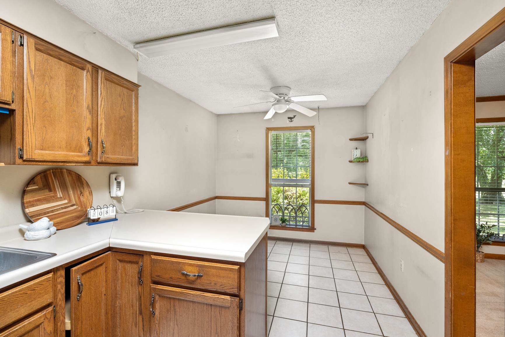 5015 Eagles Nest Lane Bartlett, TN 38002 - Photo 12 of 39 Kitchen featuring a peninsula, ceiling fan, light countertops, brown cabinets, and a textured ceiling