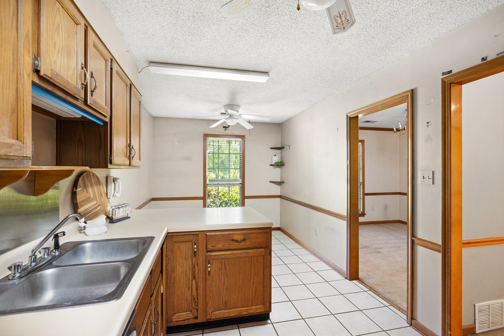 5015 Eagles Nest Lane Bartlett, TN 38002 - Photo 13 of 39 Kitchen with a peninsula, a ceiling fan, light tile patterned flooring, brown cabinets, and a textured ceiling