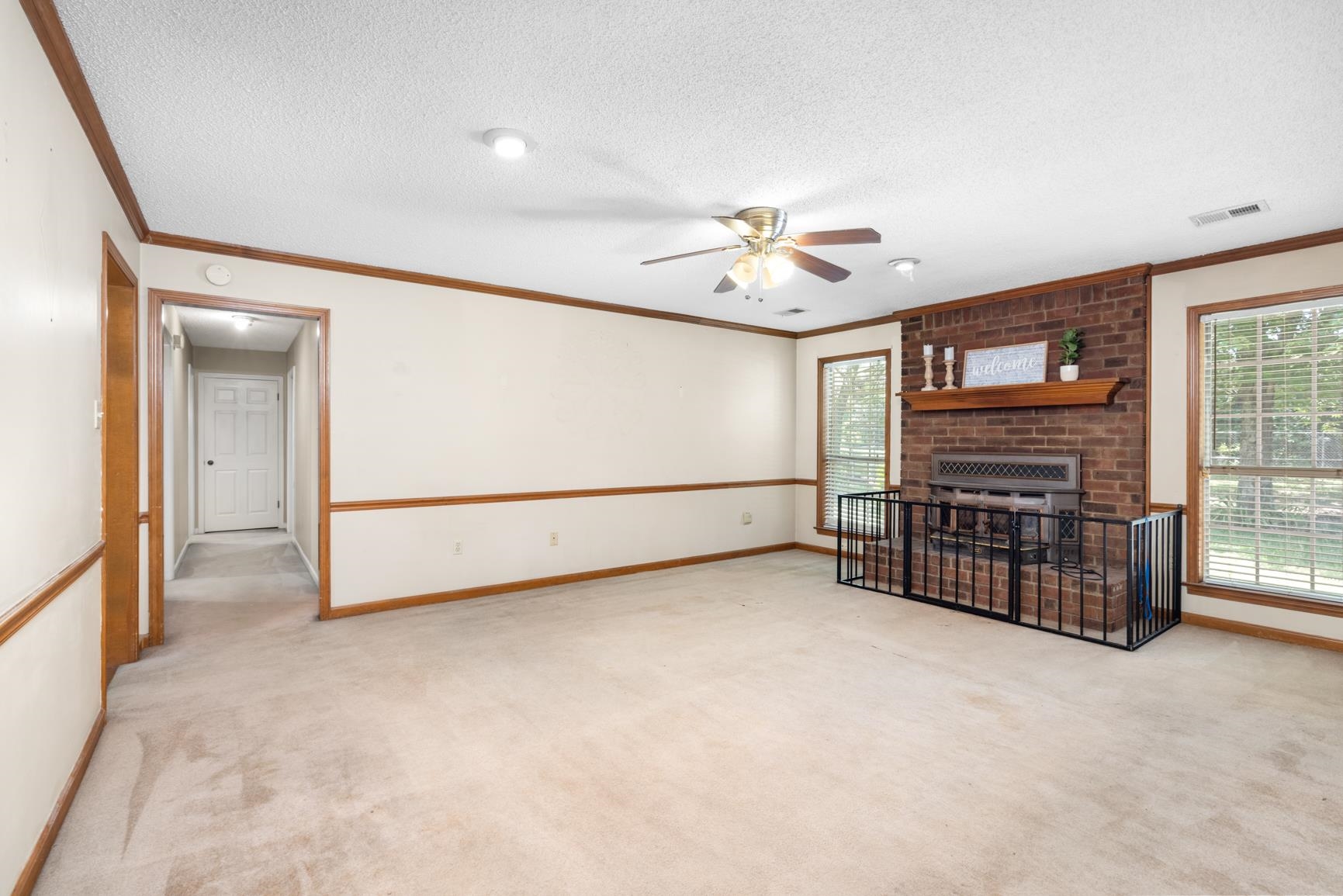5015 Eagles Nest Lane Bartlett, TN 38002 - Photo 16 of 39 Unfurnished living room with ceiling fan, carpet floors, ornamental molding, a textured ceiling, and a brick fireplace