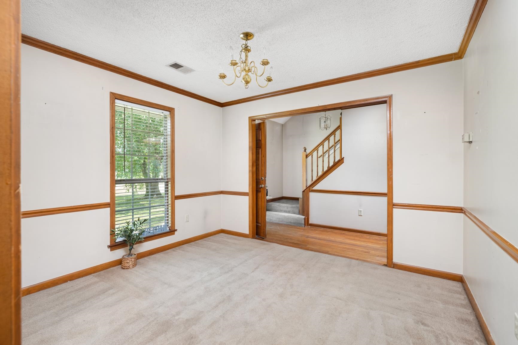 5015 Eagles Nest Lane Bartlett, TN 38002 - Photo 8 of 39 Empty room featuring a chandelier, stairway, carpet, crown molding, and a textured ceiling