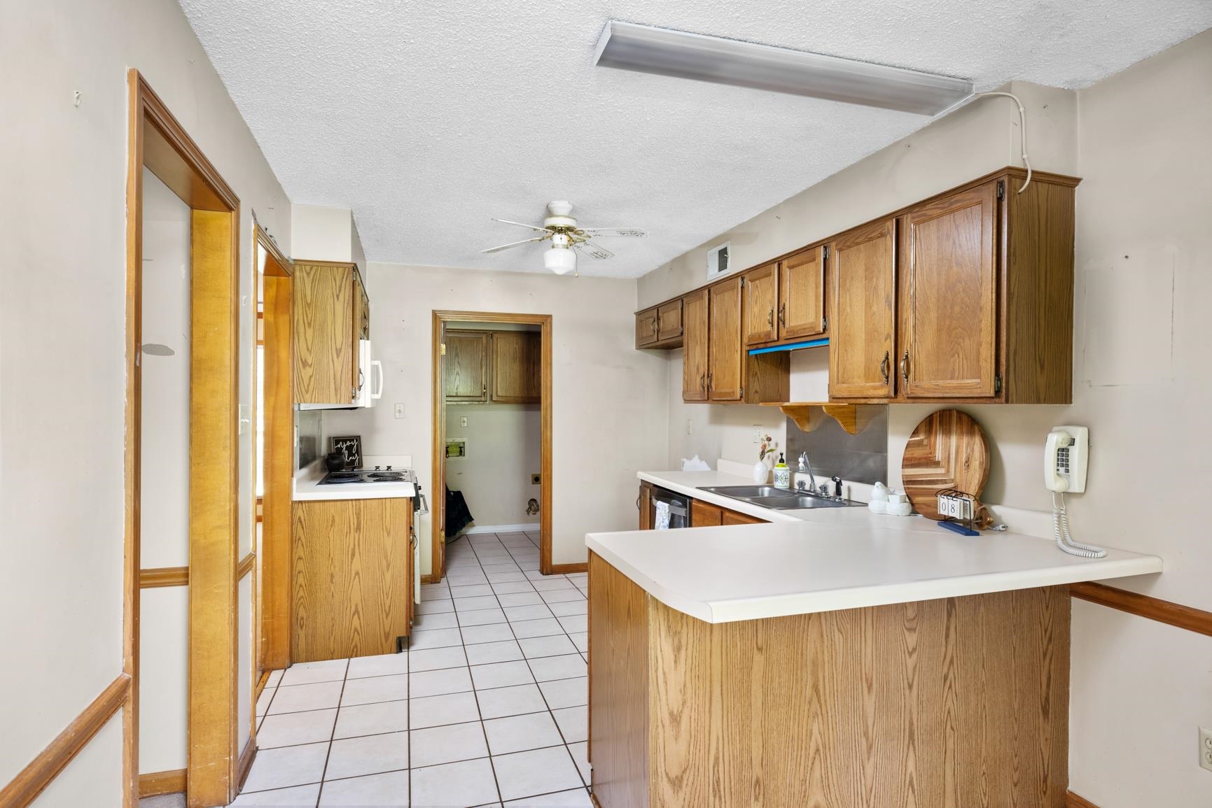 5015 Eagles Nest Lane Bartlett, TN 38002 - Photo 9 of 39 Kitchen with a peninsula, white appliances, brown cabinets, a ceiling fan, and a textured ceiling