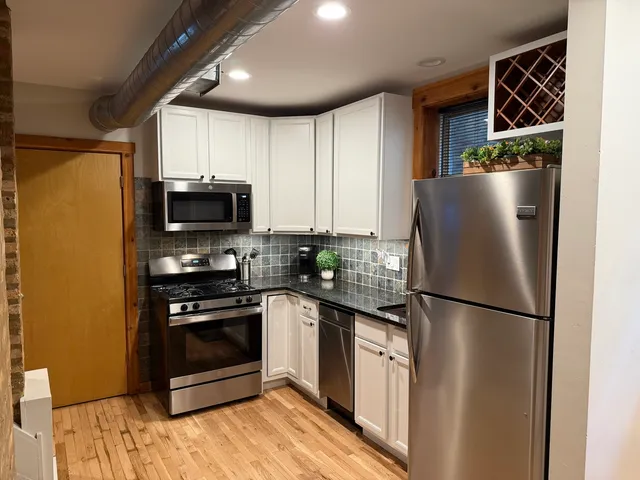 a kitchen with granite countertop a refrigerator stove and microwave