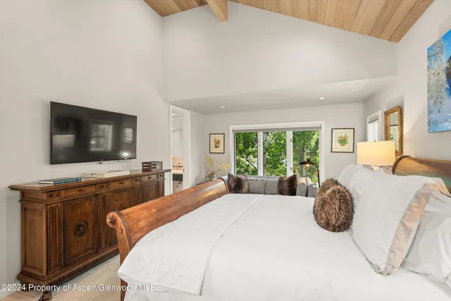 a bedroom with a bed and large windows