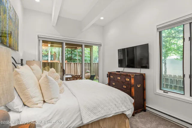 a bedroom with a bed and a flat tv screen on dresser