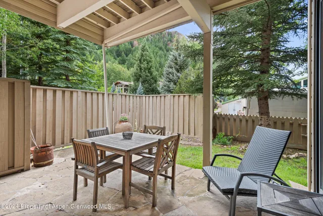 a view of a patio with a table chairs and a small yard