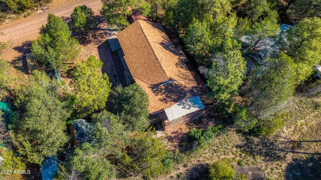 an aerial view of a house with a yard and trees all around