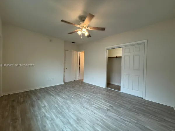 an empty room with wooden floor fan and windows