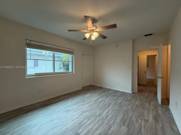 a view of an empty room with a window and wooden floor