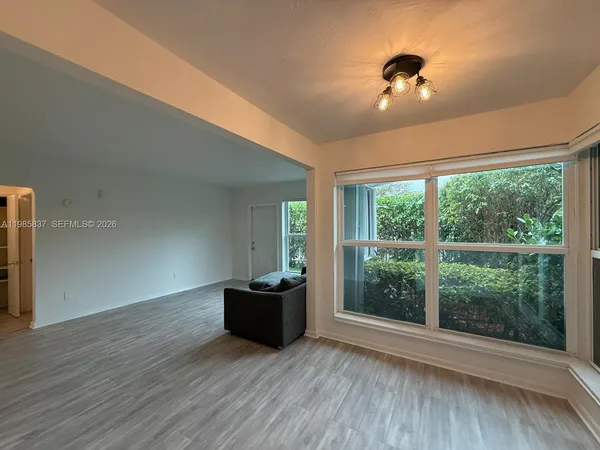 a view of an empty room with wooden floor and a window