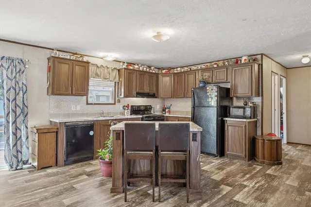 a kitchen with granite countertop a refrigerator stove top oven and sink