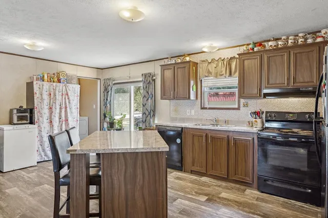 a kitchen with granite countertop a sink stove and refrigerator