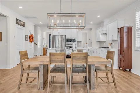 a dining room with stainless steel appliances kitchen island granite countertop a dining table chairs and white cabinets