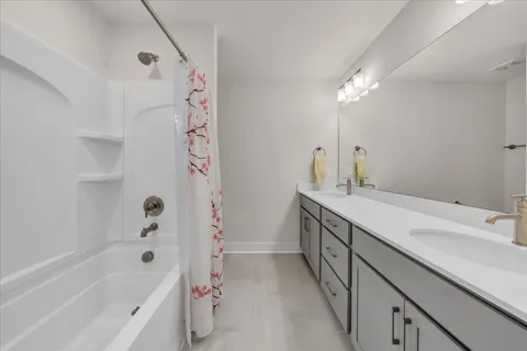 a bathroom with a double vanity sink a large mirror and shower
