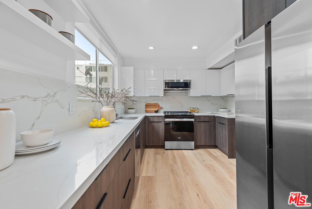 301 South Rexford Drive, Unit 2 Beverly Hills, CA 90212 - Photo 5 of 23 a kitchen with kitchen island a counter top space a sink a refrigerator and a stove top oven
