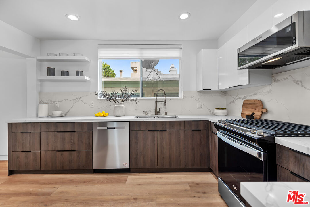 301 South Rexford Drive, Unit 2 Beverly Hills, CA 90212 - Photo 6 of 23 a kitchen with stainless steel appliances a stove a sink dishwasher and wooden cabinets with wooden floor