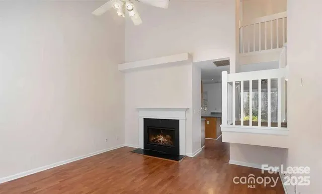 a view of an empty room with wooden floor fireplace and a window