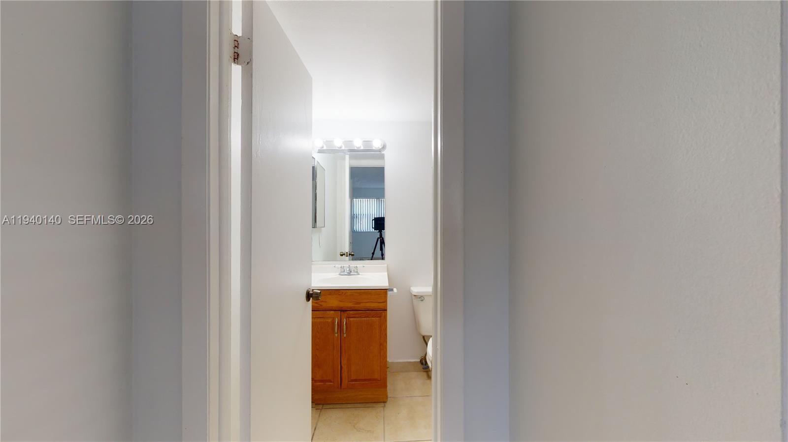 15600 Southwest 80th Street, Unit L202 Miami, FL 33193 - Photo 13 of 18 a en suite bathroom with a toilet sink and mirror